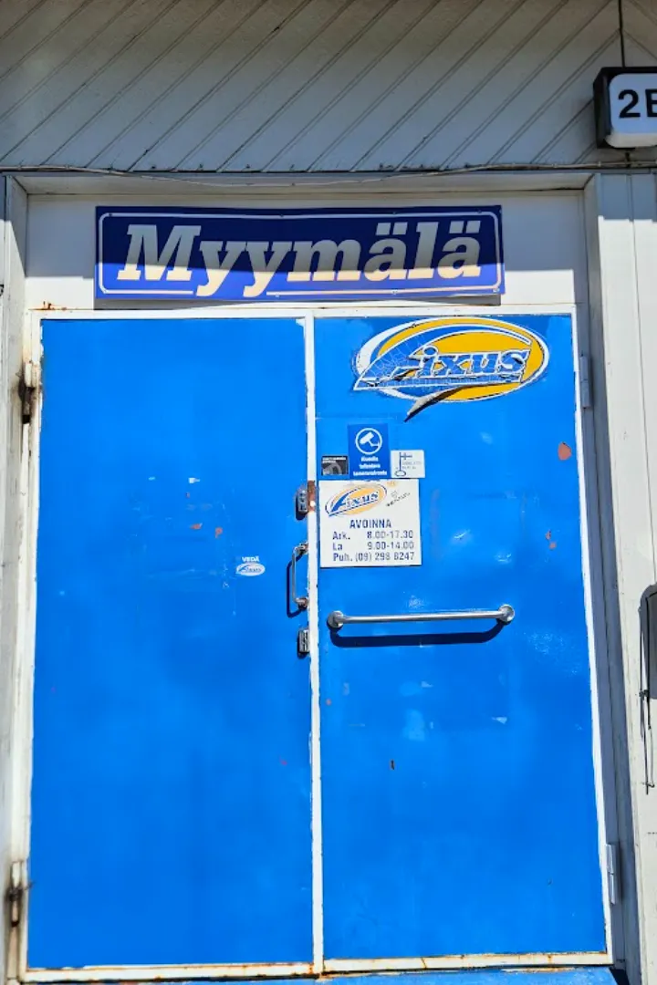 Karin Autotarvikkeen sininen pääsisäänkäynti — Myymälä-kyltti ja Fixus-tarra ovessa